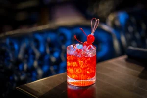 Red Valentine’s cocktail with ice, cherries, and candy hearts in a glass.